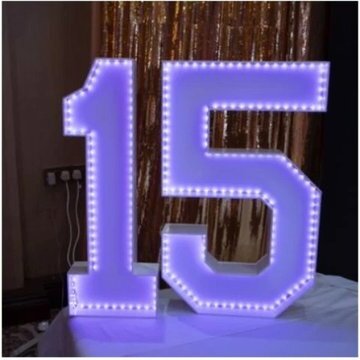 Illuminated marquee number 15 in front of a gold sequin backdrop