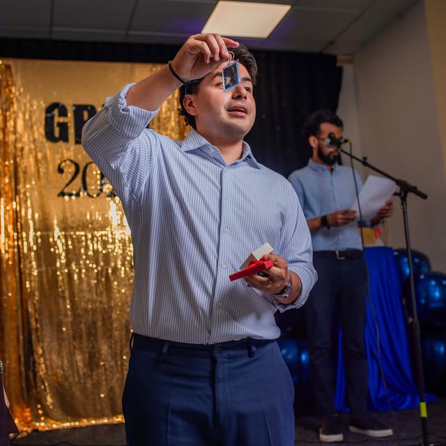 Graduation speech in front of a gold sequin backdrop